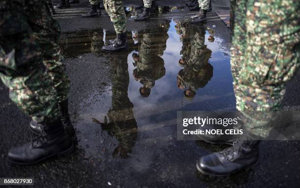 Philippine soldiers are reflected on the puddle as they arrive at the port of Manila on October 30 with some 500 personnel composed of marines,...