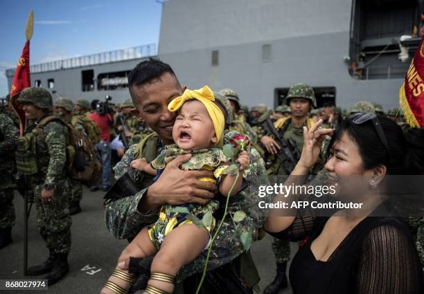 Philippine soldier hugs his baby daughter as he arrives at the port of Manila on October 30 with some 500 personnel composed of marines, sailors,...