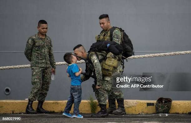 Philippine soldier kisses his son as he arrives at the port of Manila on October 30 with some 500 personnel composed of marines, sailors, aviators...