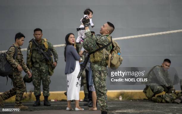 Philippine soldier holds his baby daughter as he arrives at the port of Manila on October 30 with some 500 personnel composed of marines, sailors,...