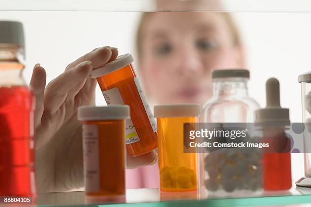 person grabbing bottle of medicine - badezimmerschrank stock-fotos und bilder