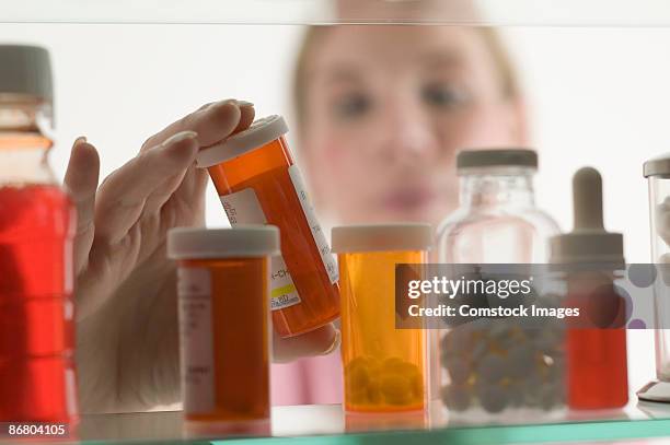 person grabbing bottle of medicine - armoire de toilette photos et images de collection