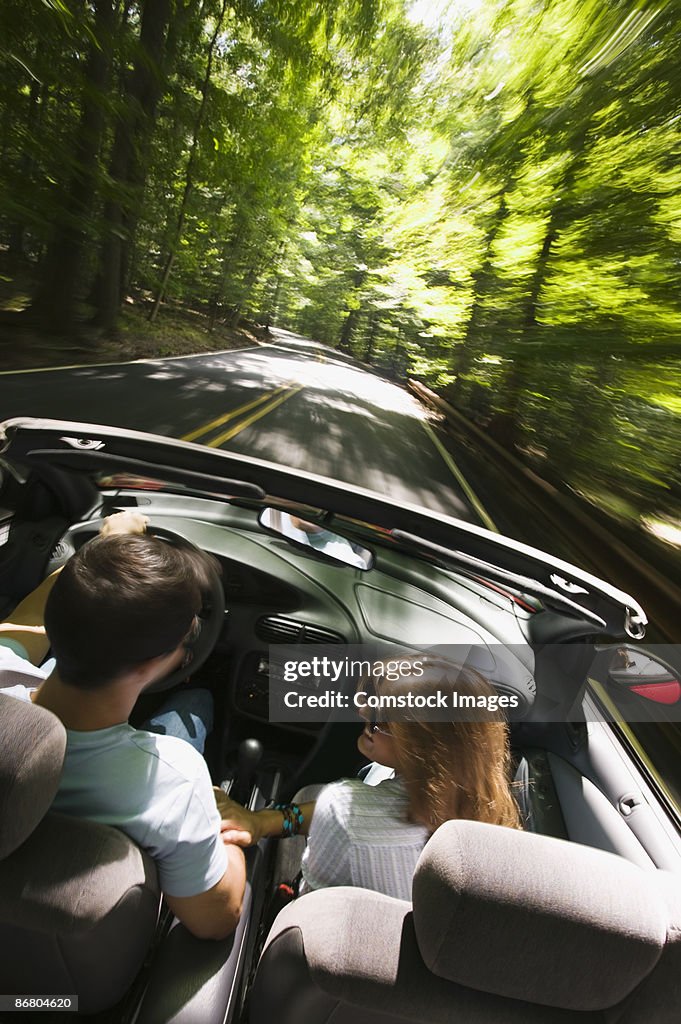 Couple driving along forest road