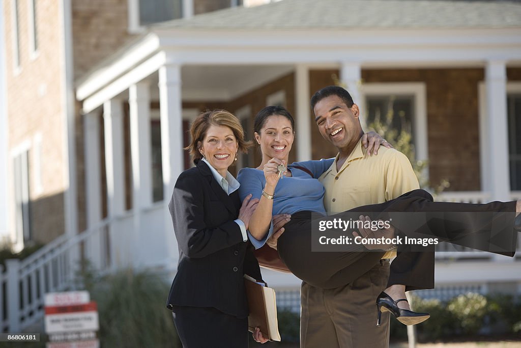 Couple standing outside home with real estate agent