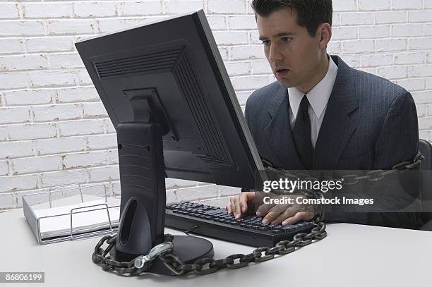 businessman chained to his computer - gevangene stockfoto's en -beelden