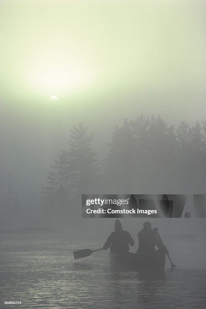 People canoeing on foggy river