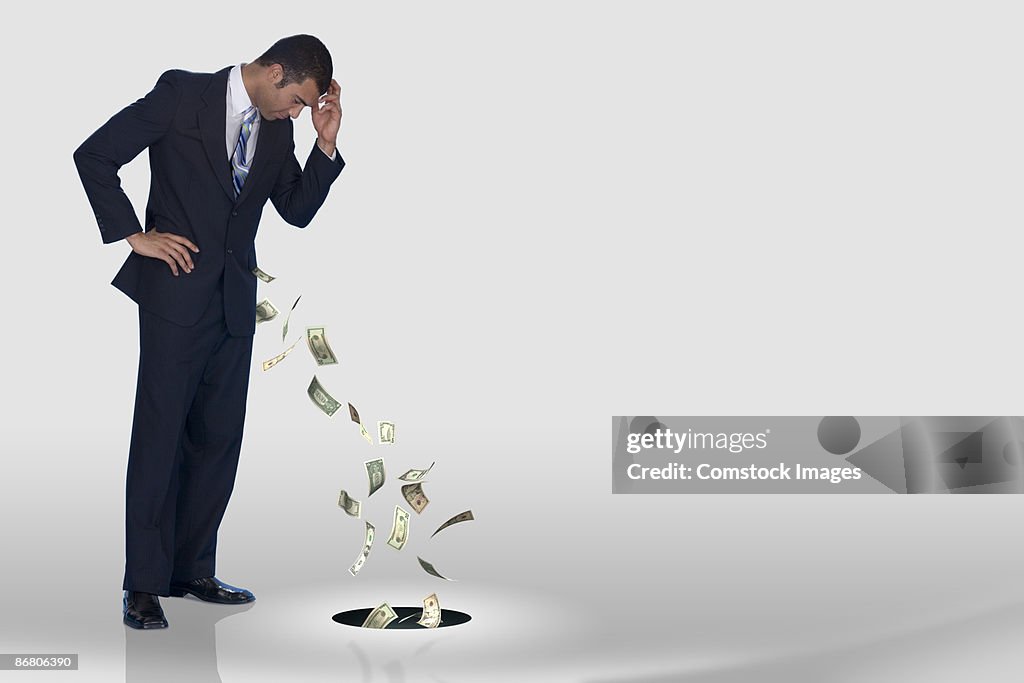 A businessman losing his money down the drain
