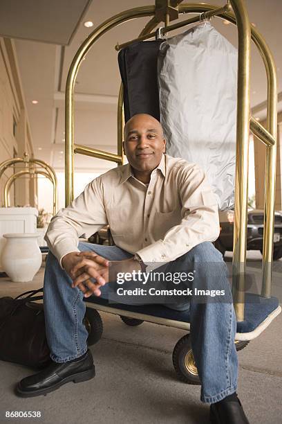 man sitting on hotel luggage rack - chariots et charrettes photos et images de collection