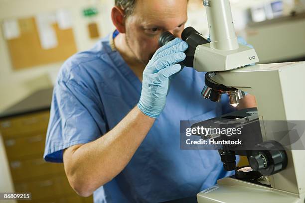 scientist analyzing a sample through a microscope - sewer scope stock pictures, royalty-free photos & images