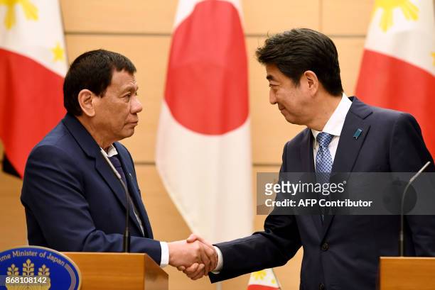 Philippines President Rodrigo Duterte shakes hands with Japanese Prime Minister Shinzo Abe at the end of their signing ceremony and joint remarks...