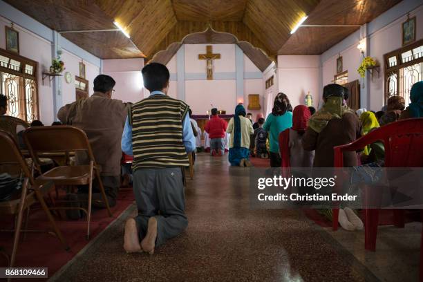 Kalimpong, India A man is kneeing and praying barefoot towards the altar inside a church in Kalimpong.