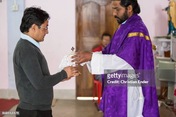 Kalimpong, India A man is giving a jar to a priest while a ceremony inside a church in Kalimpong.