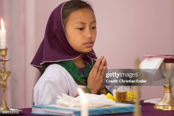 Kalimpong, India A young girl as a altar server with a tunicle is standing and praying in front of a altar inside a church near Kalimpong.