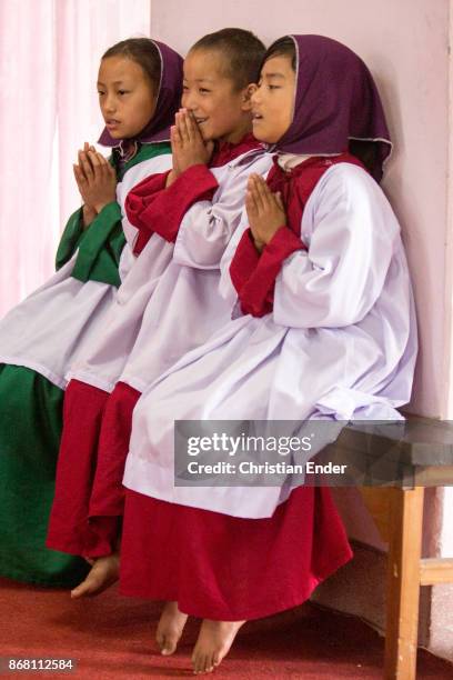 Kalimpong, India A young girl as a altar server with a tunicle singing barefoot inside a church in Kalimpong.