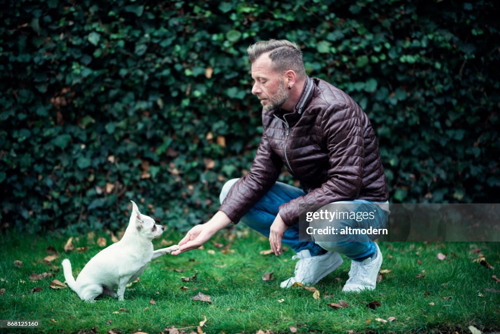 Hipster Männer mit seinem kleinen Hund vor einer Wand Efeu