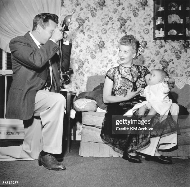 Actor Desi Arnaz photographing Lucille Ball hold their son Desi Jr., California, January 1953.