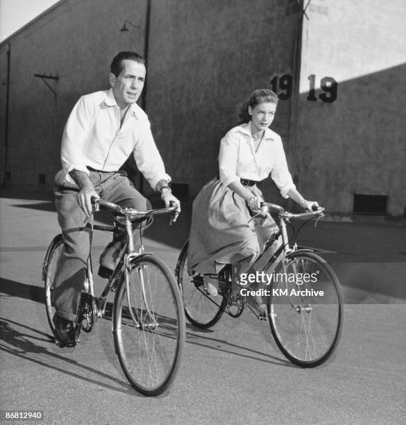 American actor Lauren Bacall and her husband, actor Humphrey Bogart ride bicycles while on the set of the film 'Key Largo', Hollywood, California,...