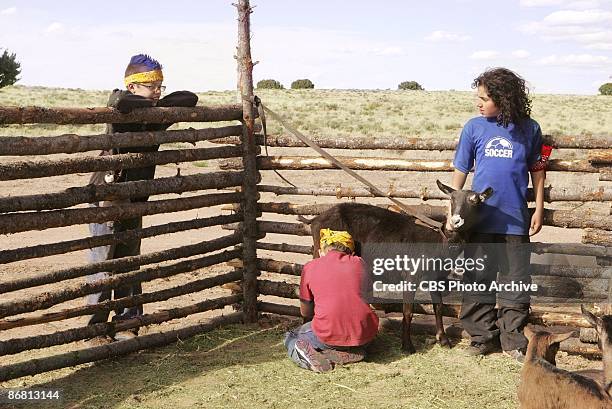 Brett watches Colton milking the goat that Guylan holds still in KID NATION on the CBS Television Network.
