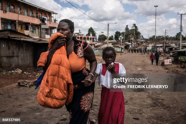 Woman and her daughter cover their mouths to protect themselves from police tear gas near a standoff between Kenyan police and supporters of Kenyan...