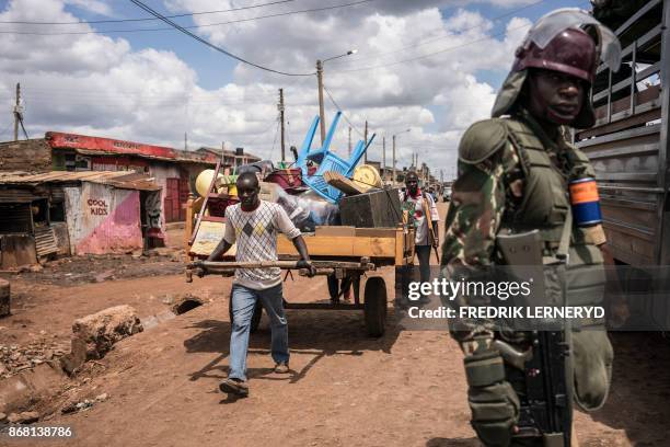 Man move his belongings with a cart next to a policeman, near a standoff between Kenyan police and supporters of Kenyan opposition leader, in...