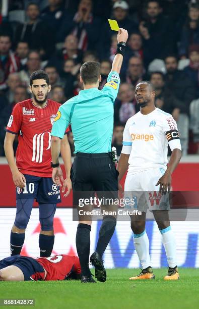 Patrice Evra of OM receives a yellow card from referee Francois Letexier while Yassine Benzia of Lille looks on during the French Ligue 1 match...