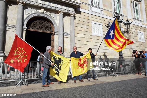 Some people wave flags from Occitania, Flanders, Wallonia and Catalan Estelada in front of the 'Generalitat' palace in Barcelona on October 30, 2017....