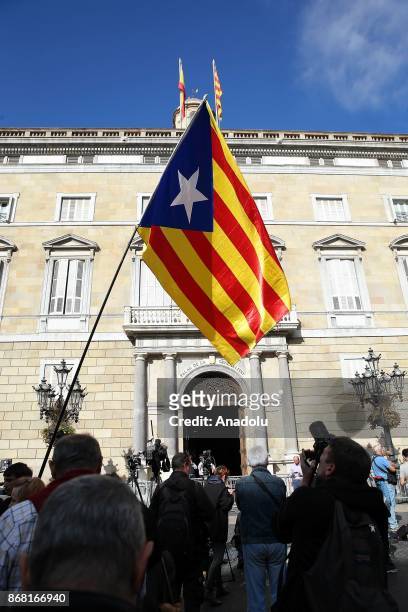 Catalan independence supporter flies a Catalan Estelada flag in front of the 'Generalitat' palace in Barcelona on October 30, 2017. Spain enters...