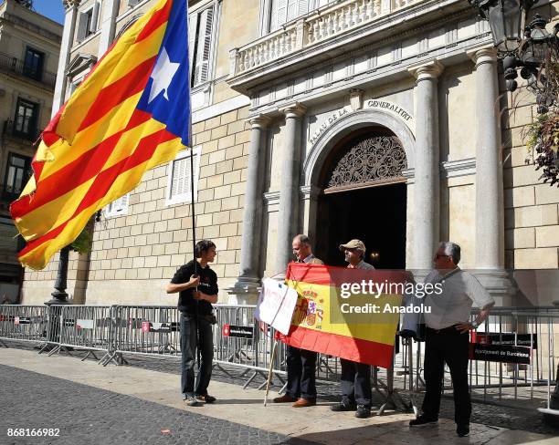 Some people unfold a Spanish flag as another man waves a Catalan pro-independece flag in front of the 'Generalitat' palace in Barcelona on October...