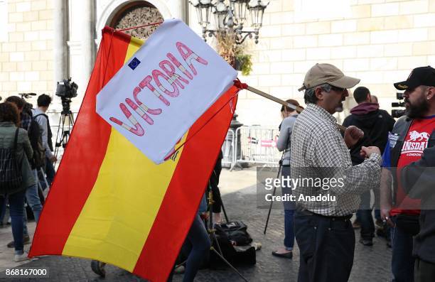 Spanish pro-unionist with a Spanish flag and a banner chats with another man in front of the 'Generalitat' palace in Barcelona on October 30, 2017....