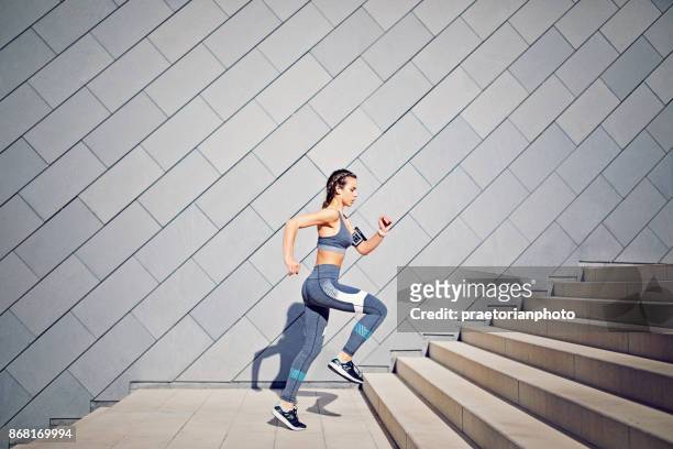 girl is runing on the city stairs and listening the music - sportswear stock pictures, royalty-free photos & images