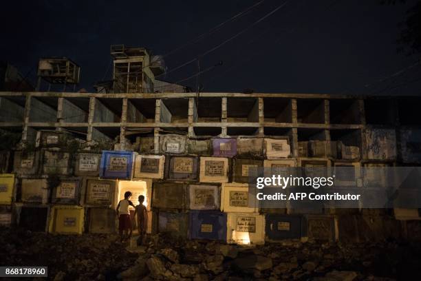 Children collect melted candles at Navotas public cemetery in Manila on October 30, 2017. Millions of Filipinos will flock to cemeteries on November...