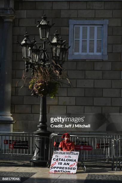 An independence supporter sits outside the Palau Catalan Regional Government Building as Catalonia returns to work following last week's decision by...