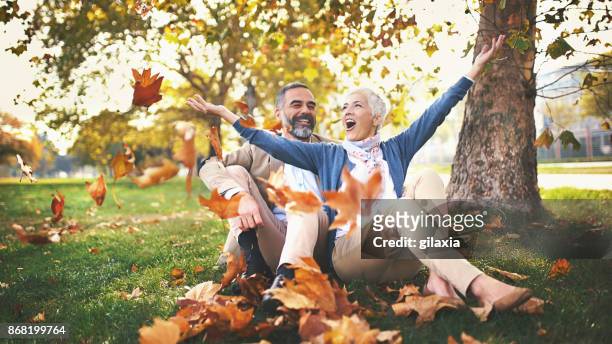 mid aged couple having fun in a park. - season stock pictures, royalty-free photos & images