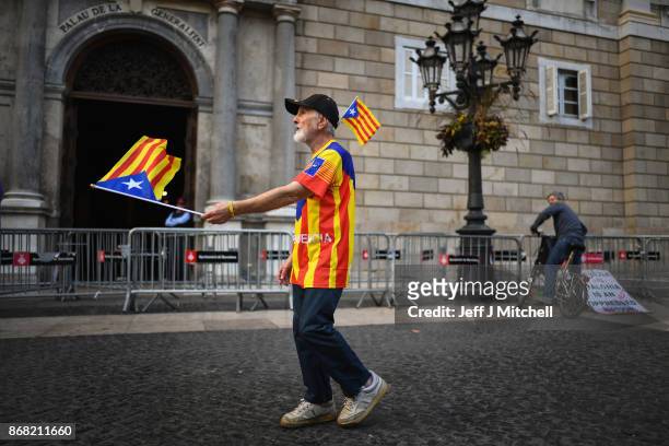 An independence supporter waves a flag outside the Palau Catalan Regional Government Building as Catalonia returns to work following last week's...