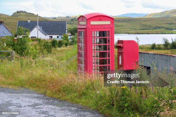 red telephone box and mailbox next to the road during rainy weather - staffin stock pictures, royalty-free photos & images