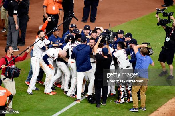 Alex Bregman of the Houston Astros is mobbed by teammates after hitting the game-winning RBI single in the 10th inning during Game 5 of the 2017...