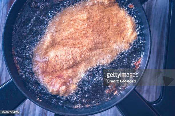 frying wiener schnitzel in deep oil in a cooking pan - wiener schnitzel stock pictures, royalty-free photos & images