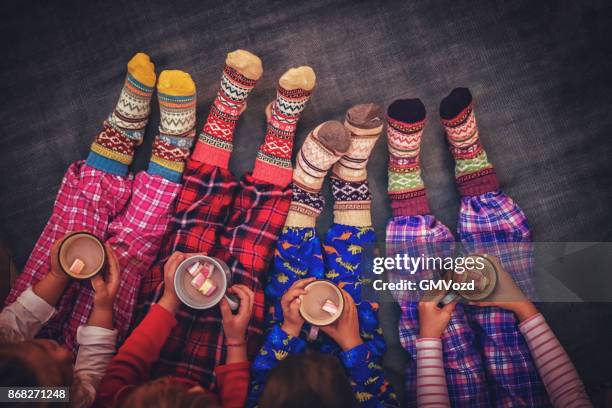 mignons petits enfants en pyjamas et noël chaussettes boire un chocolat chaud avec des guimauves pour noël - chaussette noel cheminée photos et images de collection