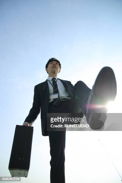 low angle view of businessman walking with briefcase - business man walking with a bag in asia stockfoto's en -beelden