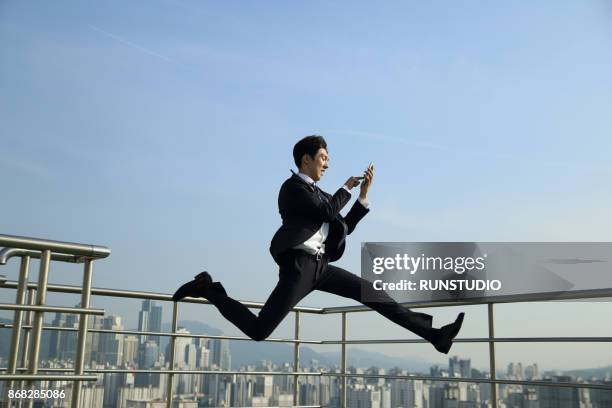 businessman running and jumping, with cell phone - completo da uomo foto e immagini stock