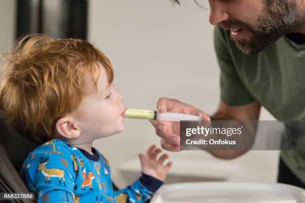 padre dando penicilina medicina enferma su bebé niño - medicina para los resfriados fotografías e imágenes de stock