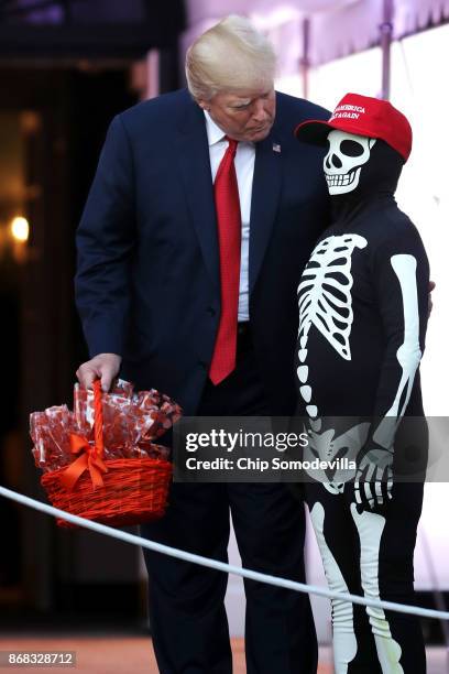 President Donald Trump talks with a child dressed as a skeleton with a "Make America Great Again" hat while hosting Halloween at the White House on...