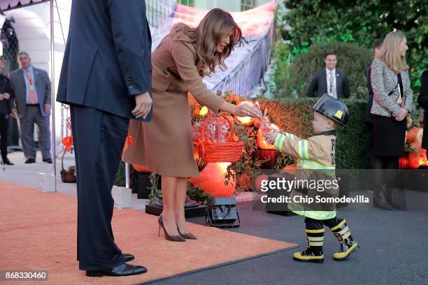 First lady Melania Trump gives a cookie to little trick-or-treater while hosting Halloween at the White House on the South Lawn October 30, 2017 in...