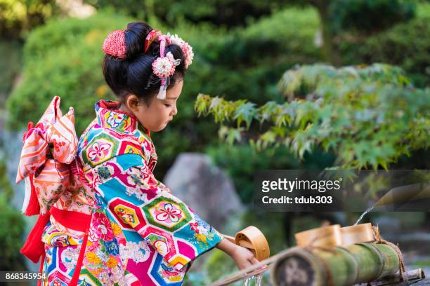 en ung japansk flicka klädd i en traditionell kimono högtidligen tvätta händerna - ceremony bildbanksfoton och bilder