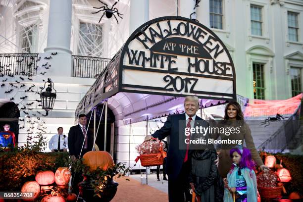 President Donald Trump, center, and U.S. First Lady Melania Trump, right, pose for a photograph with children dressed up in costumes during a...