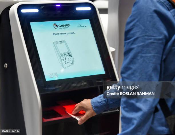 Passenger scans his passport to check-in luggage at an automated booth at the newly-opened Singapore Changi Airport's Terminal 4 in Singapore on...