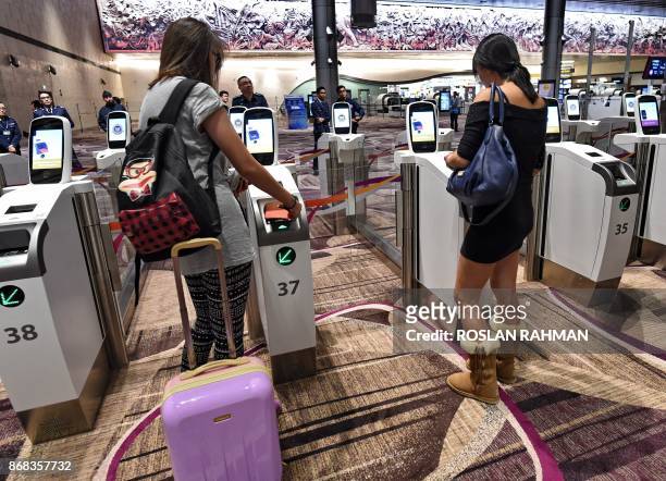 Passengers scan their passports at automated immigration gates at the newly-opened Singapore Changi Airport's Terminal 4 in Singapore on October 31,...