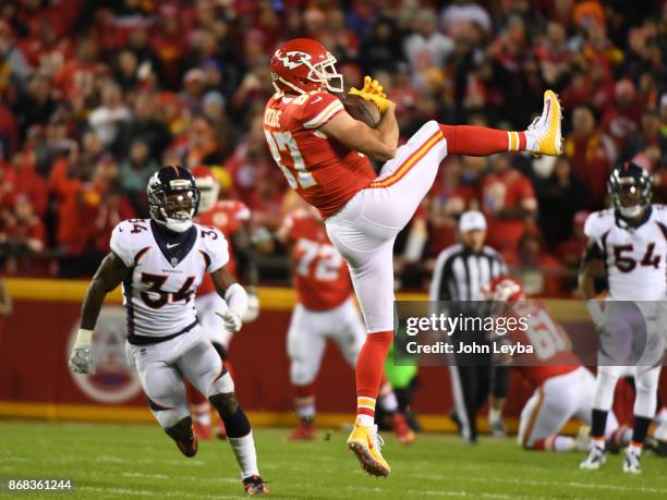 Kansas City Chiefs tight end Travis Kelce comes down with a catch in front of Denver Broncos defensive back Will Parks during the first quarter on...