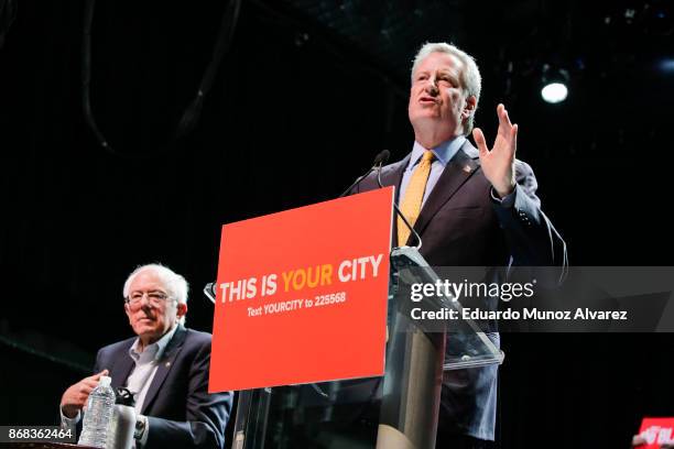 New York City Mayor Bill de Blasio speaks to supporters next to Sen. Bernie Sanders as they take part in a campaign rally on October 30, 2017 in New...