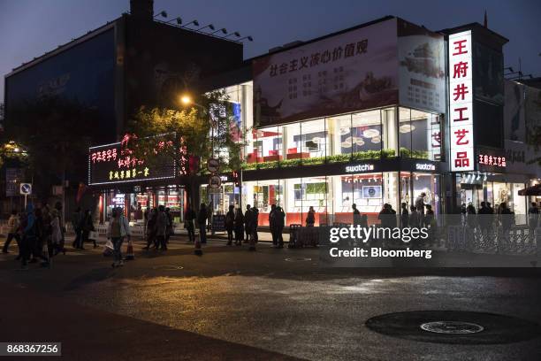 Pedestrians walk past a Swatch Group AG store on Wangfujing Street at night in Beijing, China, on Monday, Oct. 23, 2017. The worlds second-largest...